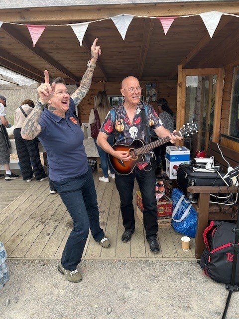 Female veteran dances whilst David Hood from Music in Hospitals and Care plays his guitar and sings