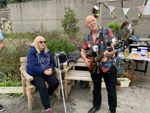 David Hood from Music in Hospitals and Care performs on his guitar whilst a family member watches on