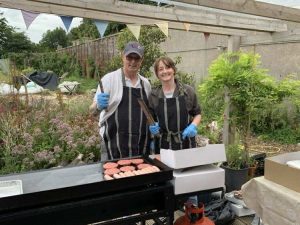 Staff members Kev and Eilidh pose behind a BBQ during our BBQ at Linburn