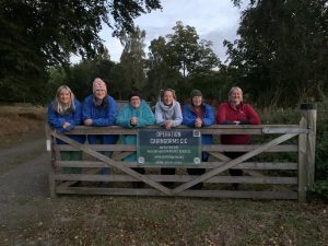 Female veterans wit OP Cairngorms staff standing behind a gate with OP Cairngorms banner attached