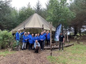 Female veterans standing in front of a yurt tent with OP Cairngorm staff members and two dogs