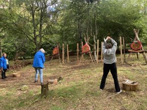 Two female veterans prepare to throw axes at targets and one female looks on