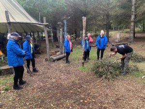 Female veterans look on as a staff member of OP Cairngorms demonstrates using sheers