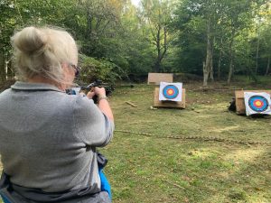 The back of a female veteran holding a crossbow aimed at a target