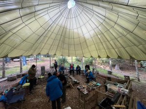 View of inside a large yurt tent of female veterans sat round fire and chat