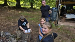 A family smile whilst a child creates art with a mallet