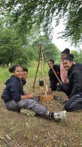 A group of children gathered around a campfire pulling faces