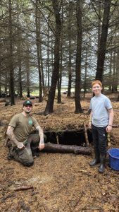 An OP Cairngorm staff member and a veterans child in front of a makeshift dugout