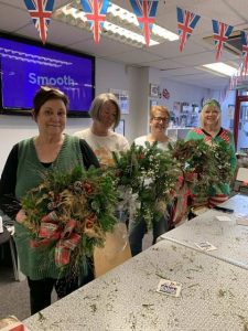 Four females showing off their wreaths made during our Christmas wreath session