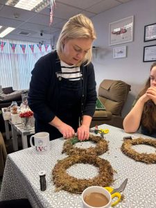 Female instructor showing ladies how to make Christmas wreaths