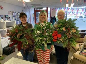 Three female veterans showing off their wreaths made during our Christmas wreath making session