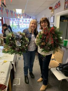 Two female veterans showing off their Christmas wreaths made during our Christmas wreath making session