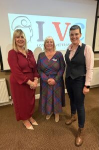 Three female veterans standing in front of sign