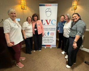 Group of female veterans standing in front of sign