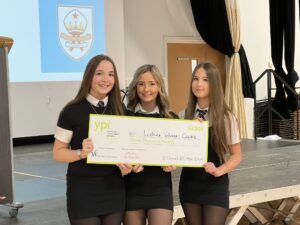 Three girls holding a large cheque for LVC