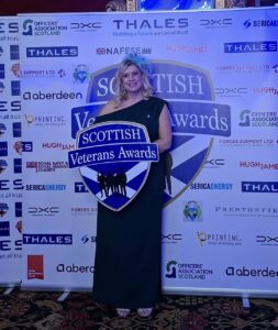 CEO, Pauline, posing for a photograph at the Veterans Awards holding a plaque.